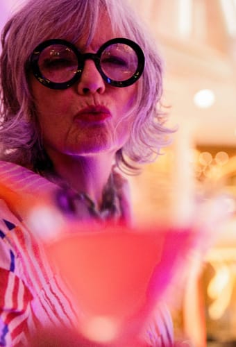 Kvinde med solbriller nyder drink i Celebrity Cruises martini bar med farvet stemningslys