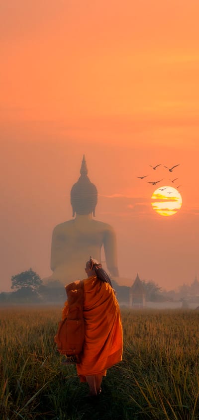 Munk går mod stor buddha figur i solnedgang i thailand