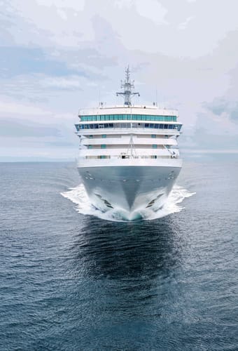 Krydstogtskib set forfra på åbent hav, der skærer sig gennem vandet