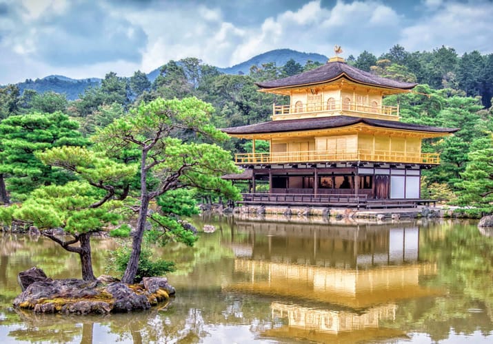 Kinkaku-ji det gyldne tempel i Kyoto omgivet af grønne træer og reflekteret i tempelsøen