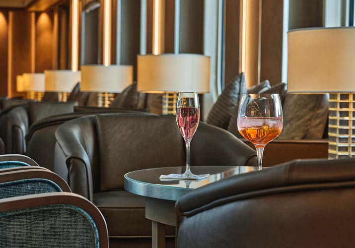 To farverige cocktails på bord mellem lænestole i eksklusiv bar-lounge ombord på Silversea